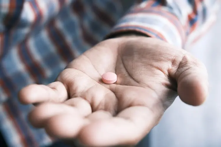 man holding out a prescription pill in his hand