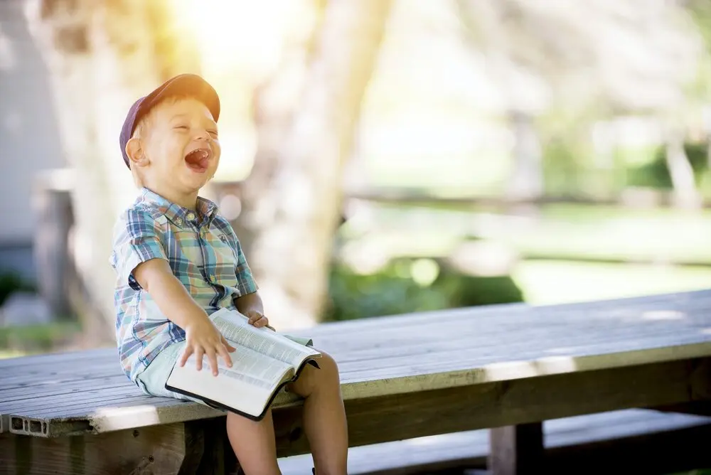 child reading a book and laughing