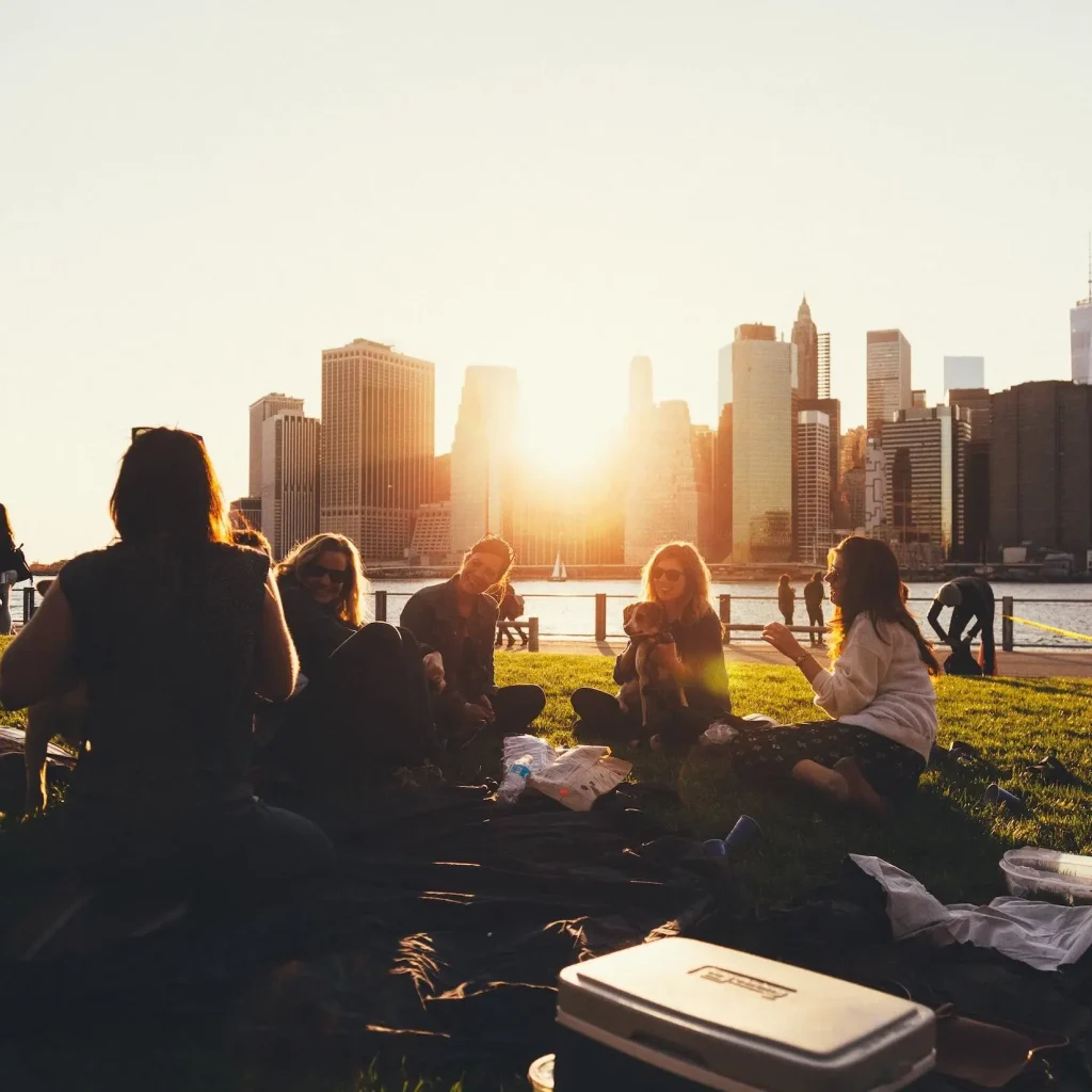 friends sitting on grass against a city landscape in the background