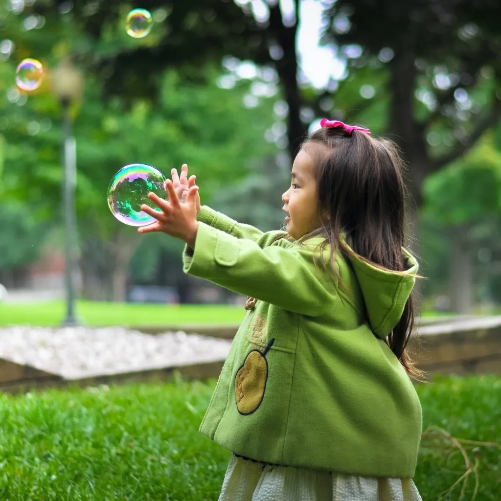 child playing with a bubble in a park