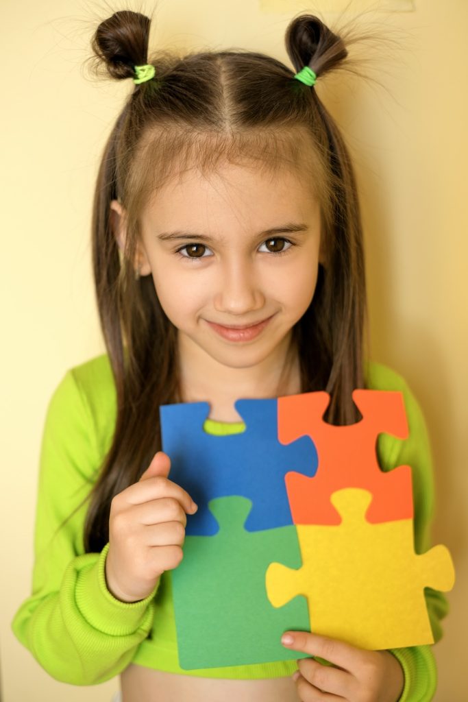 A young girl holds colorful puzzles in her hands