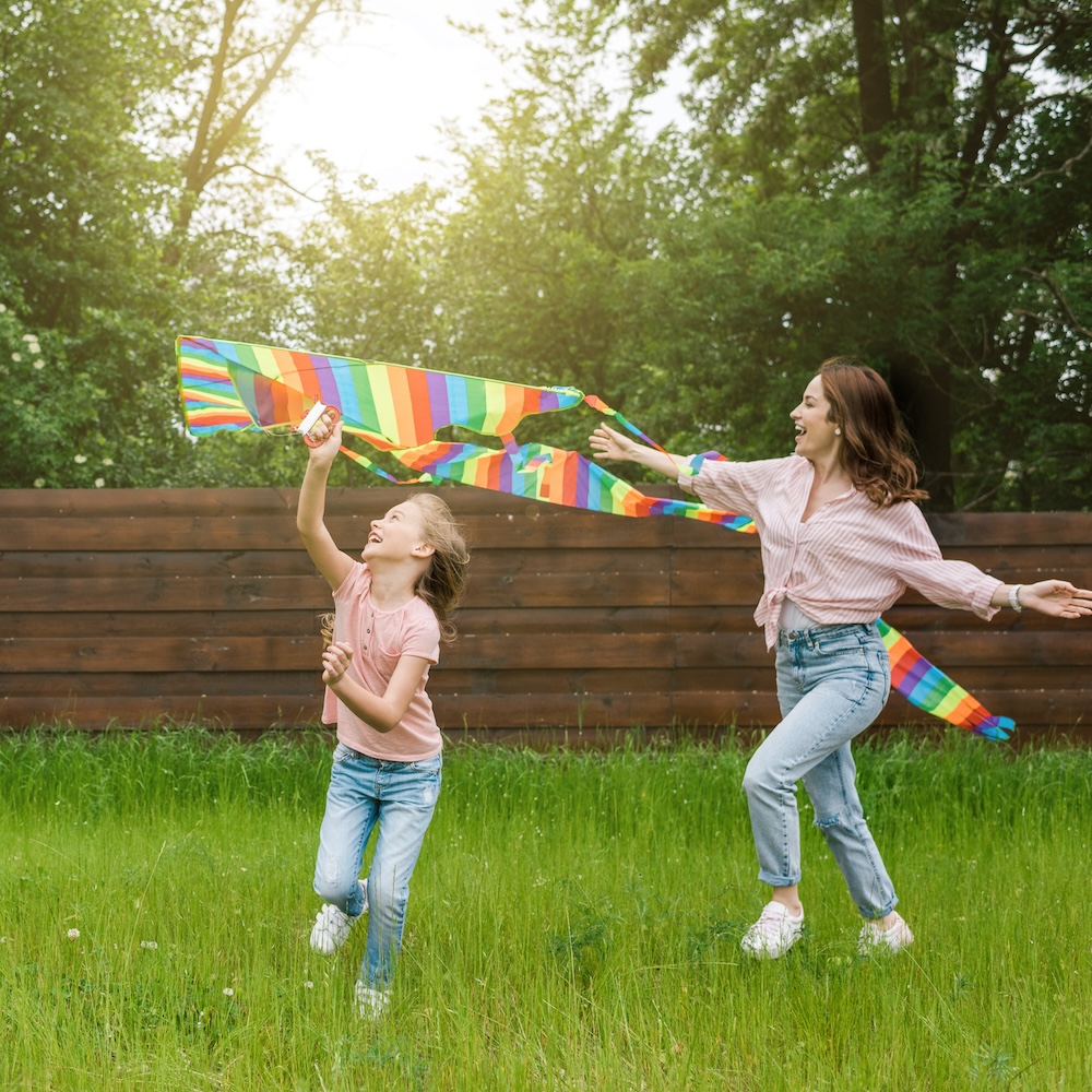 happy mother with outstretched hands near cute kid with colorful kite