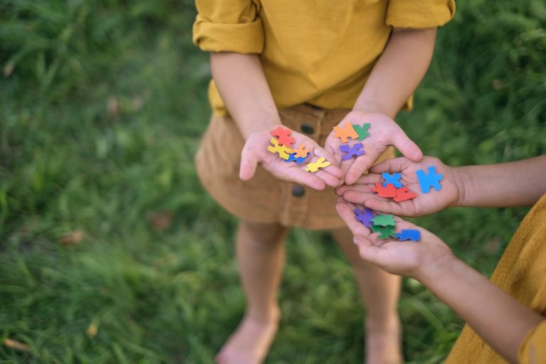 Children hold pieces of colored puzzles in their palms as a sign of support and solidarity with people with autism spectrum syndrome