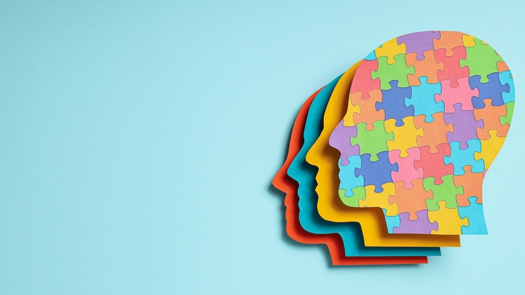 Paper human heads with colorful puzzle pieces on a light background, place for text. World autism day concept