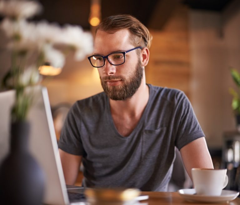 Man browsing internet on laptop about autism in his favorite coffee shop.