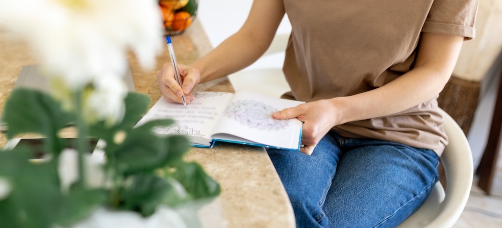 Woman writing in meditation journal, documenting symptoms of ADHD.