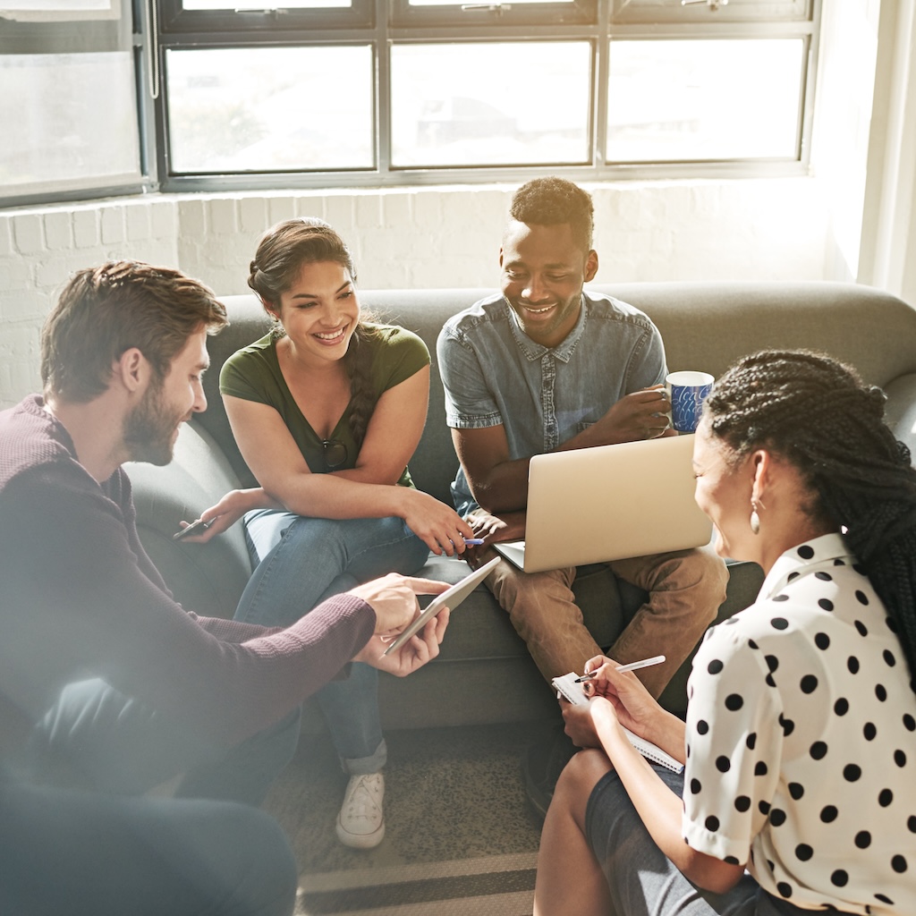 Shot of a community of likeminded people having a meeting on a sofa in a modern office.