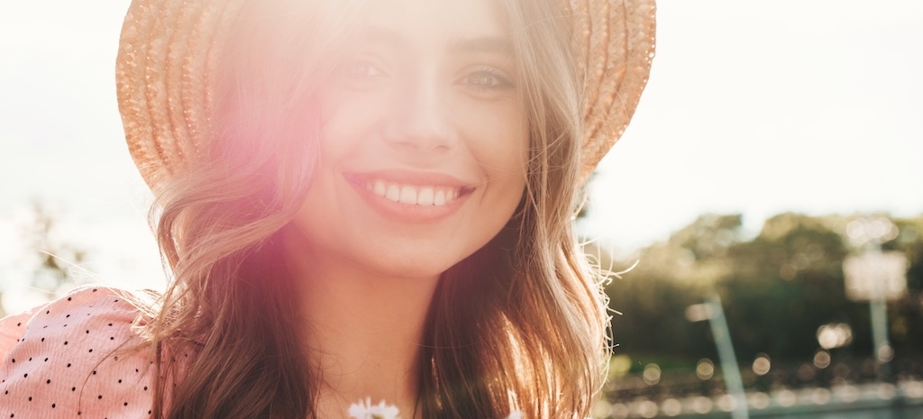 Young woman is smiling in the sun, happy to have answers about her mental health and functioning.