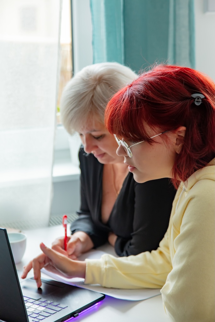 Young woman sitting with tutor at computer screen