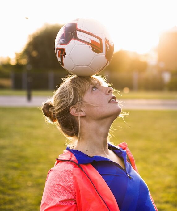 Sporty woman balancing ball on head at park