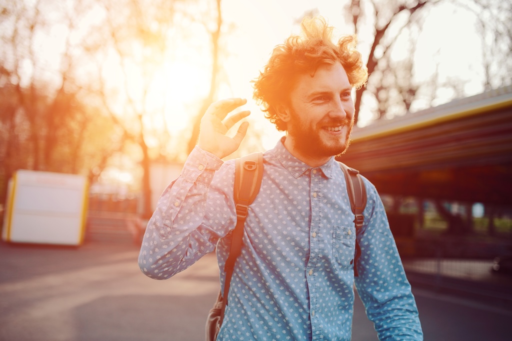 Outdoor lifestyle portrait of handsome male with red hair, walking away from sunset