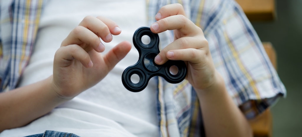 Happy little boy playing in the park with fidget spinner at the day time
