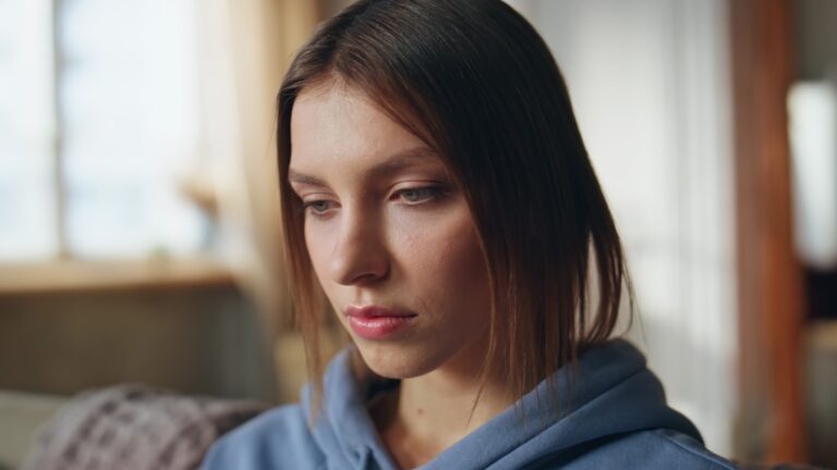 Portrait of young attractive lady with serious expression in naturally lit apartment