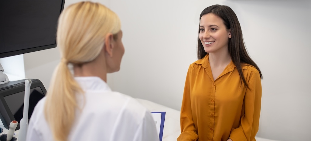 Young female patient feeling happy and smiling while talking to her doctor 