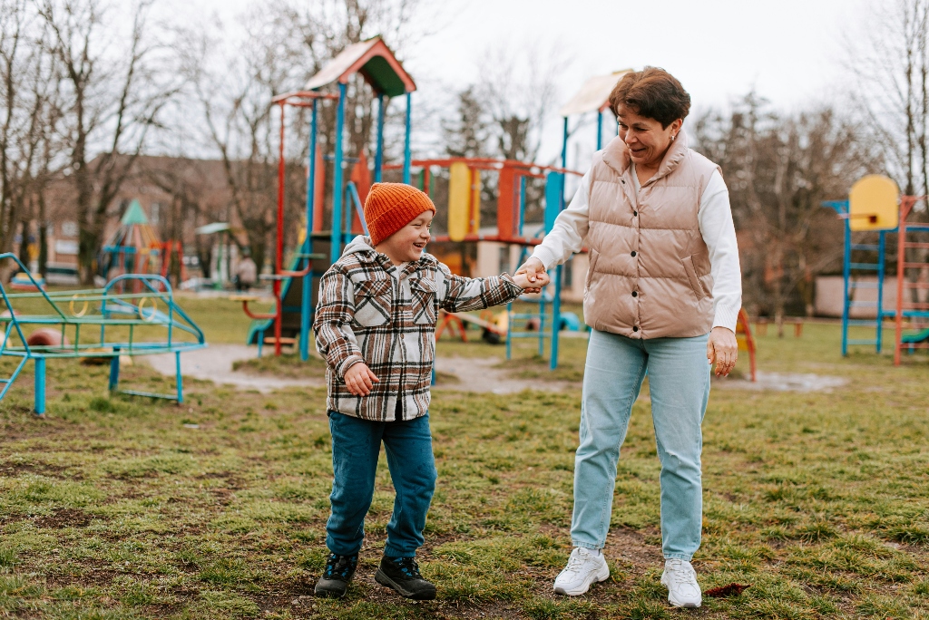 Mature adult woman holding hands, smiling and laughing, with young male child