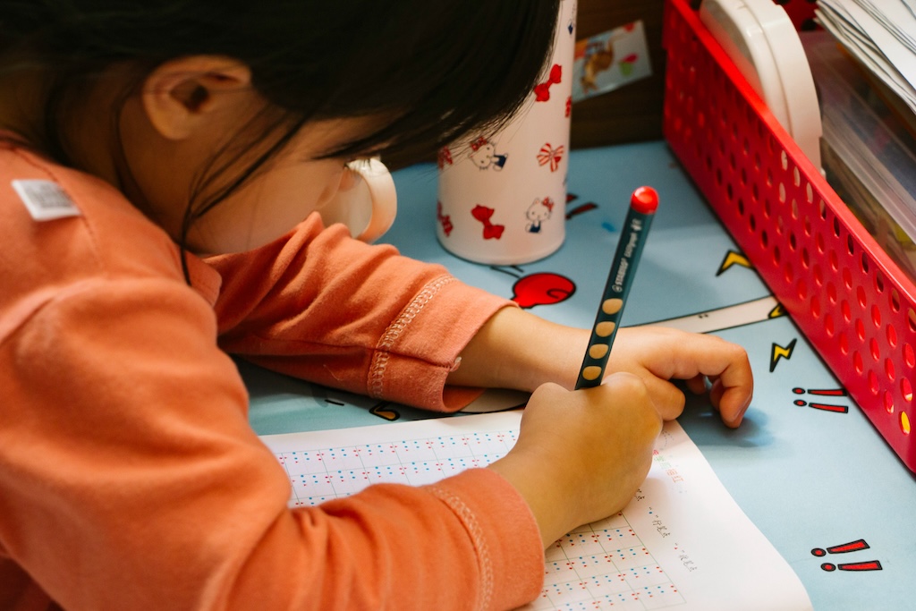 Child completing a structured writing and number task during neuropsych testing, representing assessment for dyscalculia and learning differences