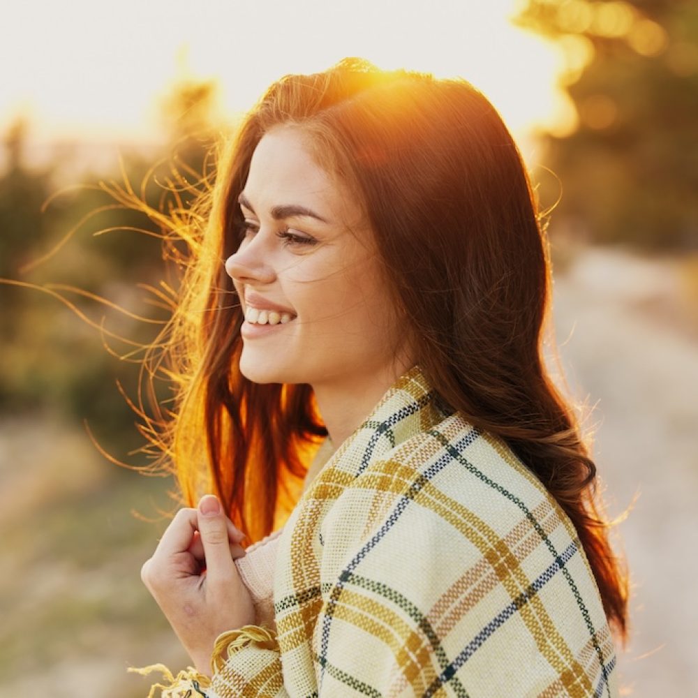 woman smiling on the path near the forest and conifers.