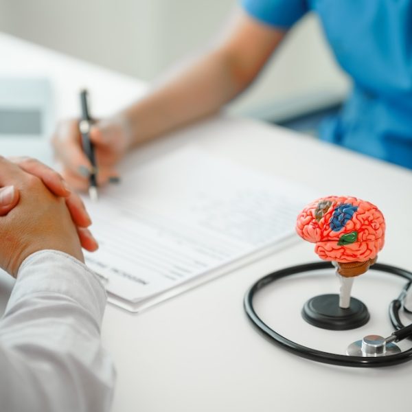 Female doctor provides crucial guidance to a male patient in clinic room with a brain model